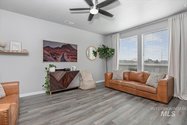 living area with a ceiling fan, baseboards, visible vents, and wood finished floors