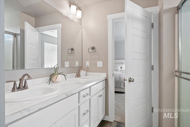 ensuite bathroom with double vanity, connected bathroom, and a sink