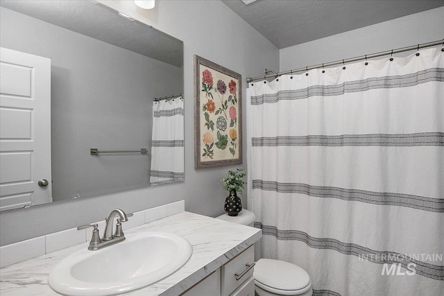 full bathroom featuring toilet, a shower with shower curtain, a textured ceiling, and vanity