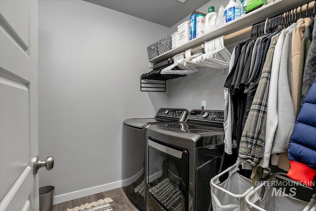 clothes washing area featuring baseboards, laundry area, wood finished floors, and washer and dryer