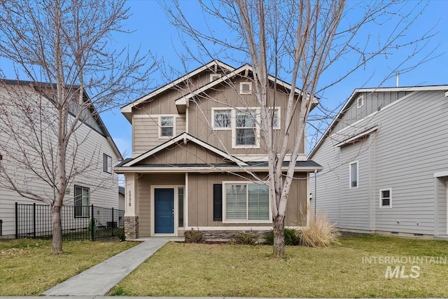 craftsman house with board and batten siding, a front yard, and fence