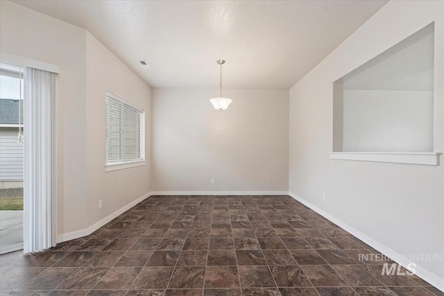 unfurnished room with stone finish floor, visible vents, and baseboards