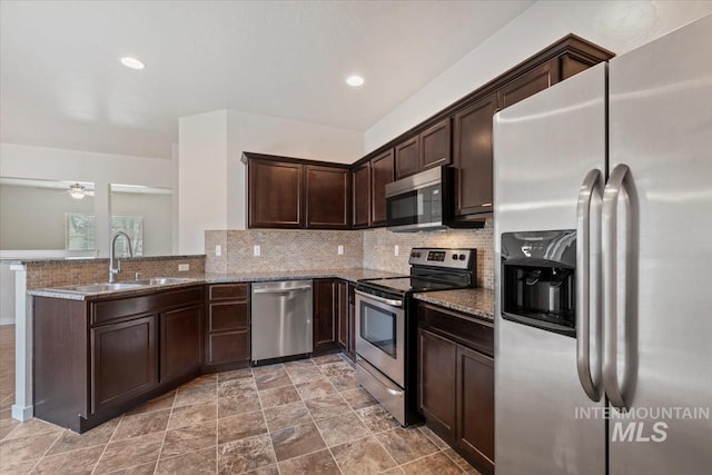 kitchen featuring a sink, stone countertops, tasteful backsplash, and stainless steel appliances