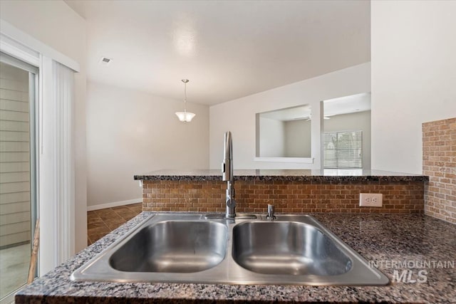 room details featuring visible vents, pendant lighting, decorative backsplash, dark stone countertops, and a sink