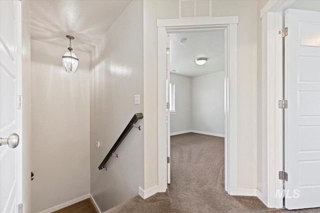 corridor with carpet flooring, an upstairs landing, visible vents, and baseboards