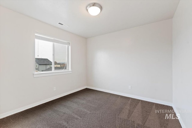 empty room featuring visible vents, baseboards, and dark carpet