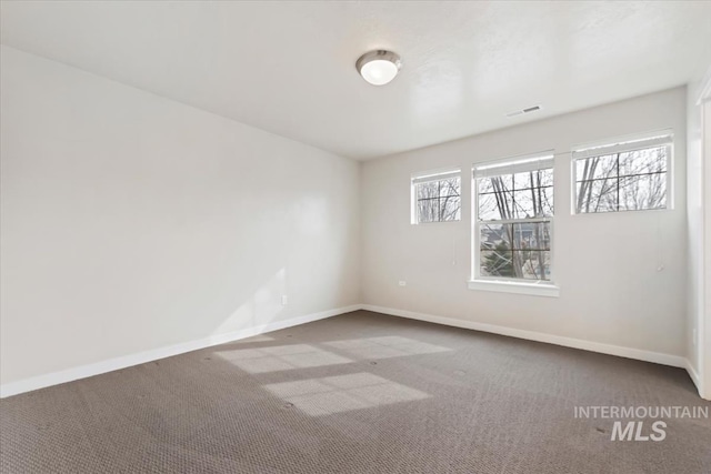 carpeted spare room featuring visible vents and baseboards