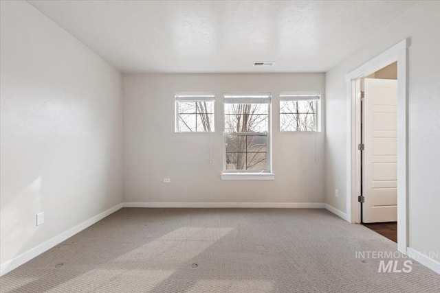 spare room with visible vents, carpet, and baseboards