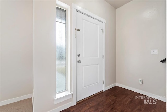 foyer entrance with dark wood-style floors, a healthy amount of sunlight, and baseboards