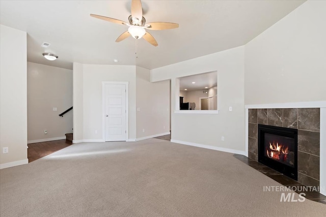 unfurnished living room with carpet flooring, a fireplace, stairs, and baseboards