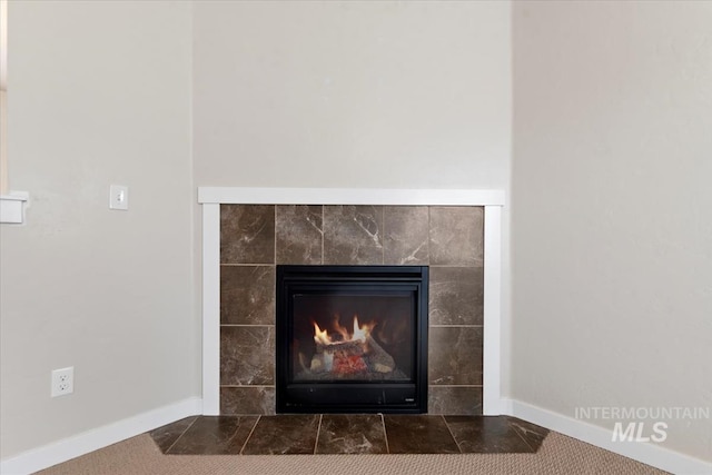 details featuring a tiled fireplace and baseboards