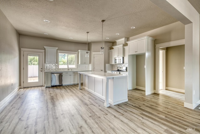 kitchen featuring a kitchen island, pendant lighting, stainless steel appliances, and white cabinetry