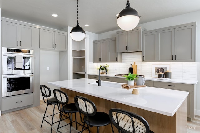 652 N Morning Glory, Eagle, ID 83616 - kitchen with light countertops, light wood finished floors, tasteful backsplash, stainless steel double oven, and gray cabinetry