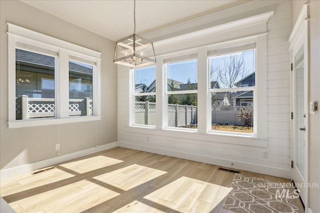 unfurnished dining area with wood finished floors, visible vents, and a healthy amount of sunlight