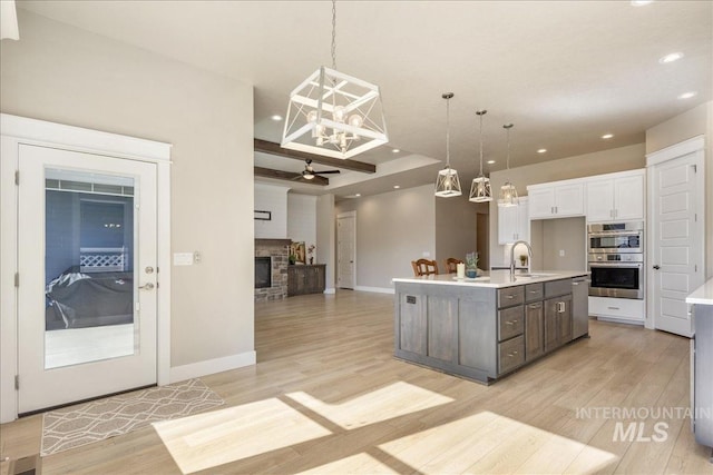 kitchen with a fireplace, stainless steel appliances, light countertops, white cabinets, and light wood-type flooring