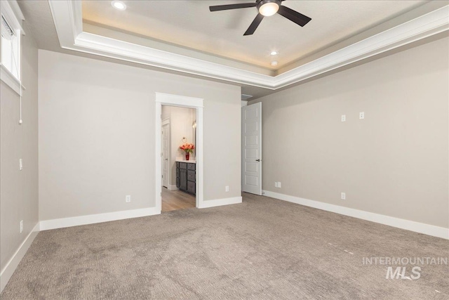 unfurnished bedroom featuring recessed lighting, baseboards, a tray ceiling, and light colored carpet