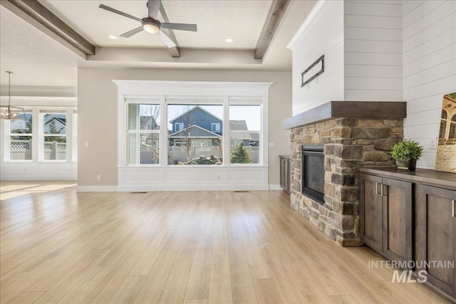 living room featuring baseboards, ceiling fan, light wood-style floors, a fireplace, and beam ceiling