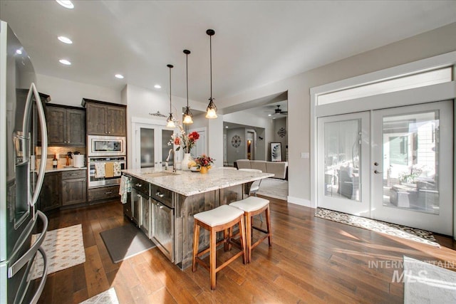 kitchen featuring appliances with stainless steel finishes, french doors, dark hardwood / wood-style floors, and a center island with sink