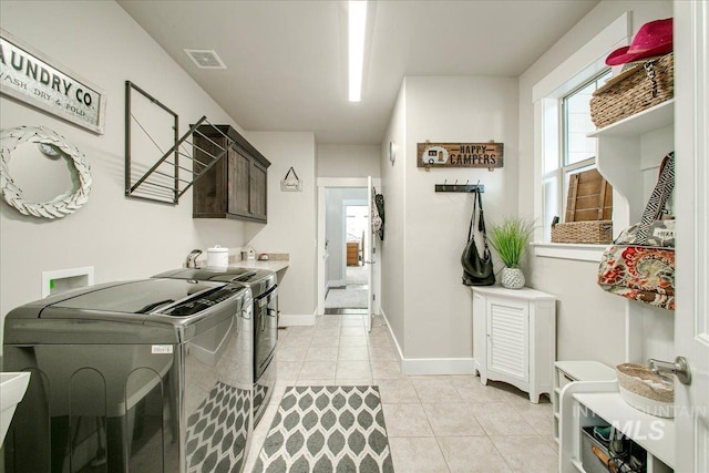 laundry area with washer and clothes dryer, light tile patterned floors, and cabinets