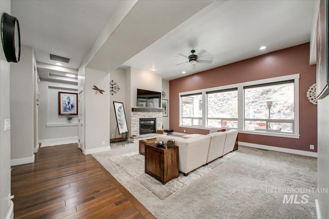 living room featuring a stone fireplace, hardwood / wood-style flooring, and ceiling fan