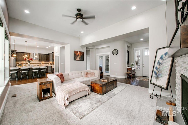 living room featuring ceiling fan, a fireplace, and dark hardwood / wood-style flooring