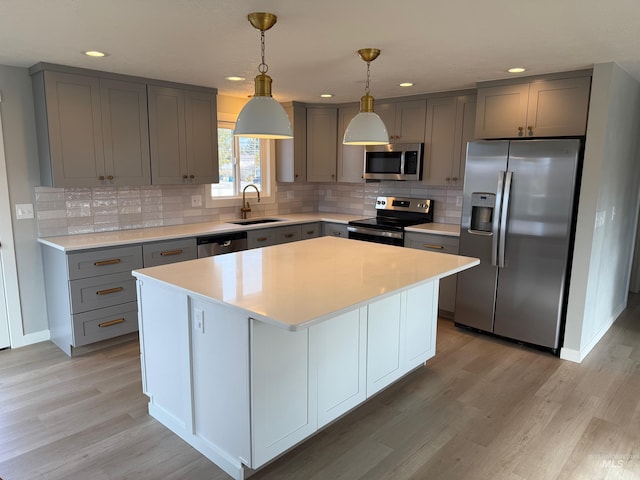 kitchen featuring sink, decorative light fixtures, a center island, and appliances with stainless steel finishes