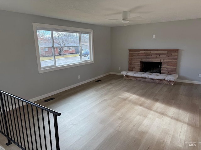 unfurnished living room featuring a fireplace, ceiling fan, and light wood-type flooring