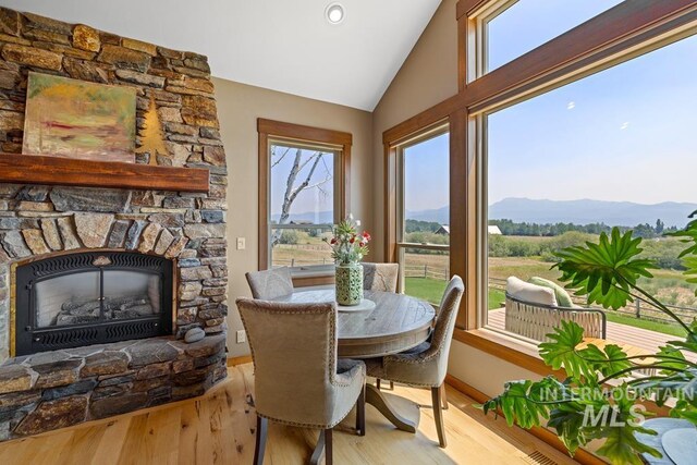41 Knob Hill Dr, Mccall, ID 83638 - dining space featuring a mountain view, vaulted ceiling, light wood-type flooring, and a stone fireplace
