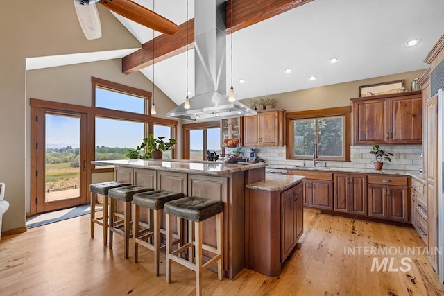 41 Knob Hill Dr, Mccall, ID 83638 - kitchen with a kitchen island, brown cabinetry, decorative backsplash, a breakfast bar, and range hood