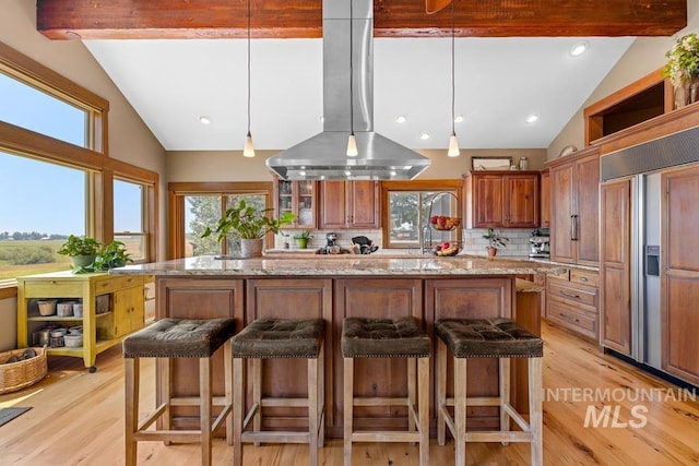 41 Knob Hill Dr, Mccall, ID 83638 - kitchen featuring island exhaust hood, backsplash, a breakfast bar area, light wood-type flooring, and beam ceiling