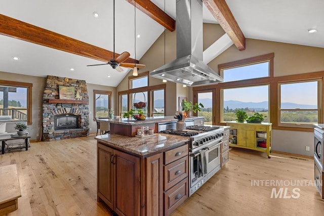 41 Knob Hill Dr, Mccall, ID 83638 - kitchen featuring island range hood, range with two ovens, a stone fireplace, beamed ceiling, and light wood finished floors
