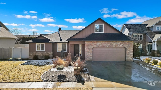 view of front facade featuring board and batten siding, driveway, an attached garage, and fence