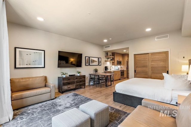 bedroom with a sink, visible vents, wood finished floors, and recessed lighting