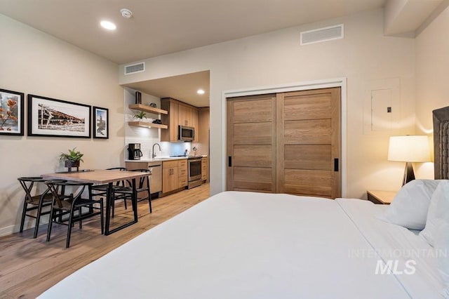 bedroom with light wood finished floors, a sink, visible vents, and recessed lighting