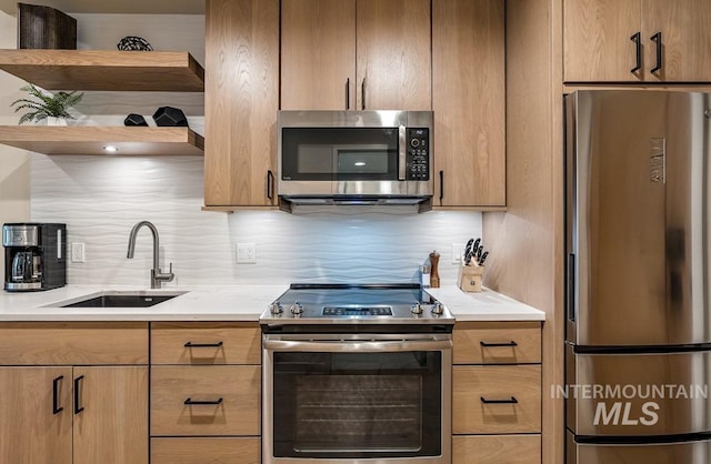 kitchen featuring appliances with stainless steel finishes, a sink, light countertops, open shelves, and backsplash