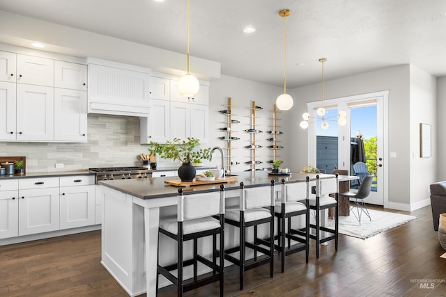 6799 E Warm Springs Ave, Boise, ID 83716 - kitchen featuring dark countertops, recessed lighting, a breakfast bar area, decorative backsplash, and dark wood-style floors
