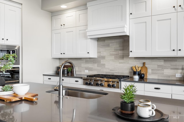 6799 E Warm Springs Ave, Boise, ID 83716 - kitchen with dark countertops, a sink, backsplash, and white cabinets