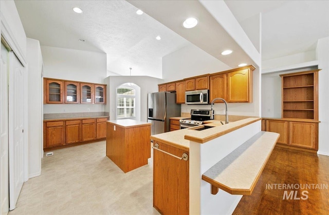 431 N David Frost St, Nampa, ID 83651 - kitchen featuring appliances with stainless steel finishes, a kitchen island, brown cabinets, recessed lighting, and glass insert cabinets