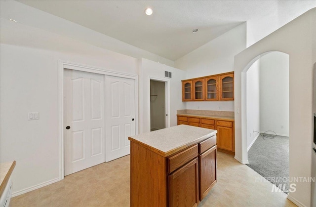431 N David Frost St, Nampa, ID 83651 - kitchen with vaulted ceiling, brown cabinetry, light countertops, glass insert cabinets, and a kitchen island