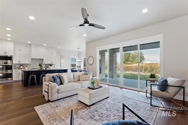 living room featuring sink, ceiling fan with notable chandelier, and dark hardwood / wood-style flooring