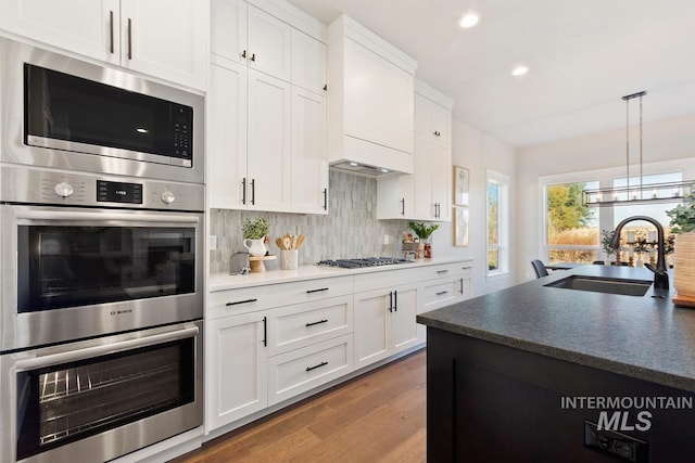 kitchen with white cabinetry, appliances with stainless steel finishes, sink, and hardwood / wood-style floors