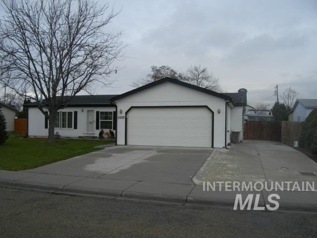 ranch-style home with a garage, concrete driveway, and fence