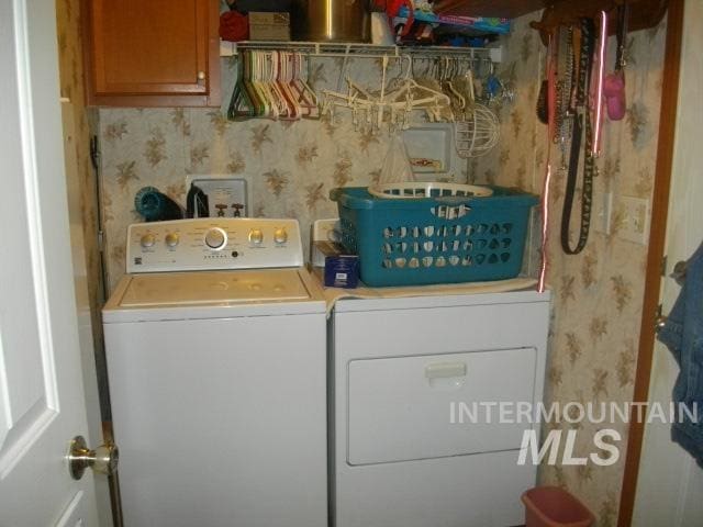 washroom featuring wallpapered walls, cabinet space, and washing machine and clothes dryer