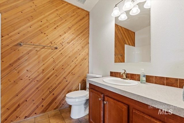 bathroom with vanity, tile patterned floors, wooden walls, and toilet