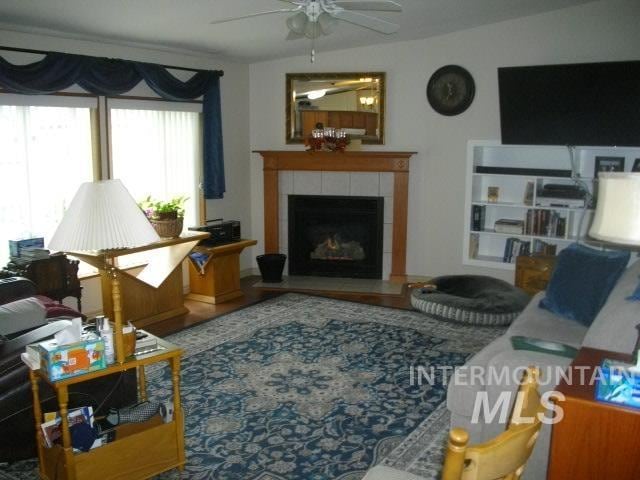 living area with a ceiling fan and a fireplace