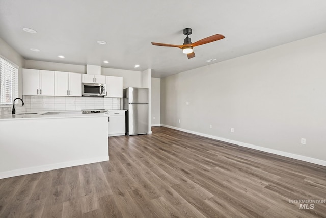 kitchen featuring white cabinetry, sink, wood-type flooring, appliances with stainless steel finishes, and decorative backsplash