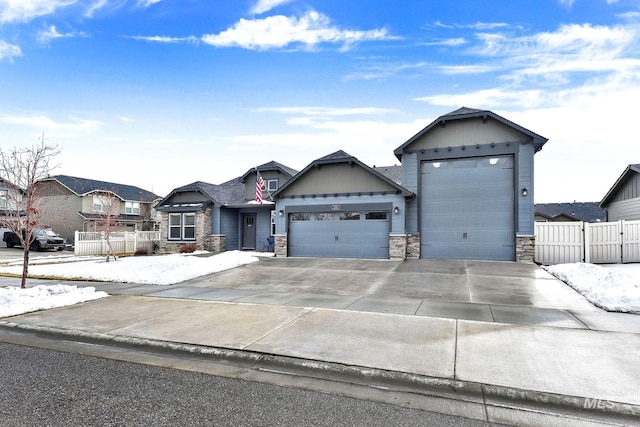 view of front of house featuring a garage, stone siding, fence, and concrete driveway