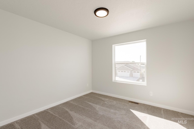 carpeted spare room featuring visible vents and baseboards