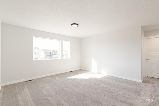 unfurnished room with visible vents, baseboards, carpet floors, and a textured ceiling