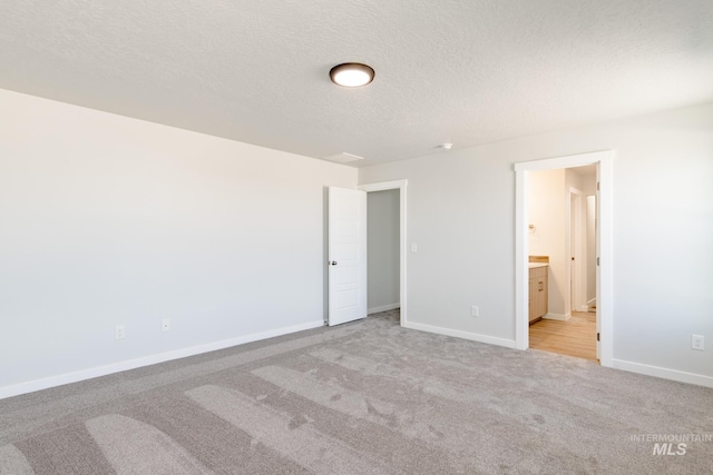 unfurnished bedroom with connected bathroom, baseboards, carpet, and a textured ceiling